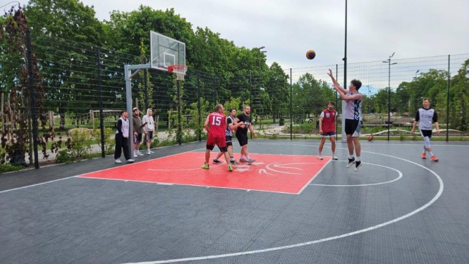 Basketbola laukumā vīriešu komanda spēlē basketbolu