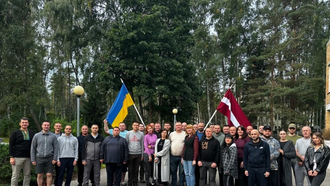 Ukrainas amatpersonu kopbilde nodaļas “Dzintari” teritorijā. Attēlā redzami 31 cilvēks; viens no viņiem tur Ukrainas karogu, bet otrs – Latvijas karogu.