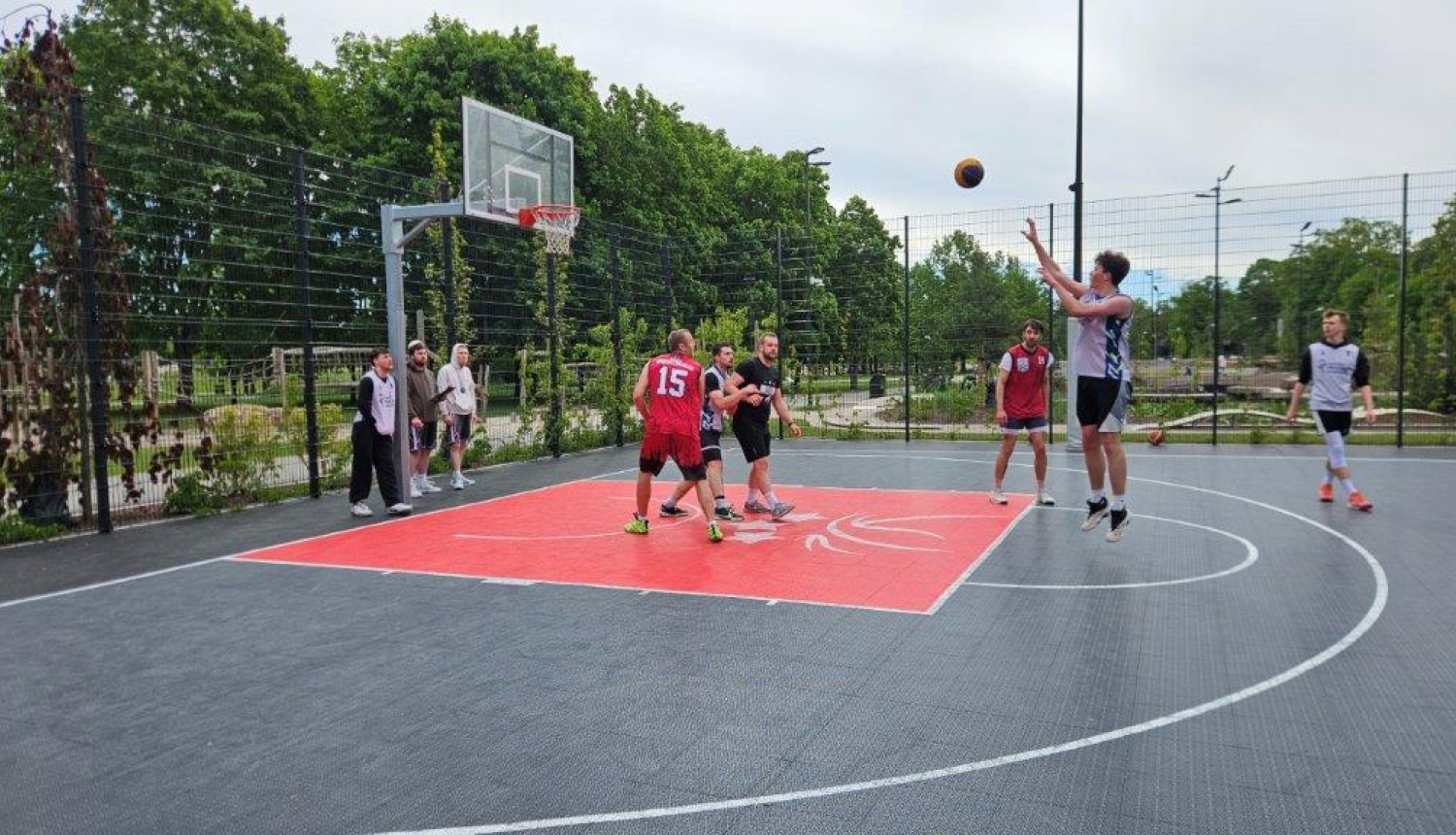 Basketbola laukumā vīriešu komanda spēlē basketbolu
