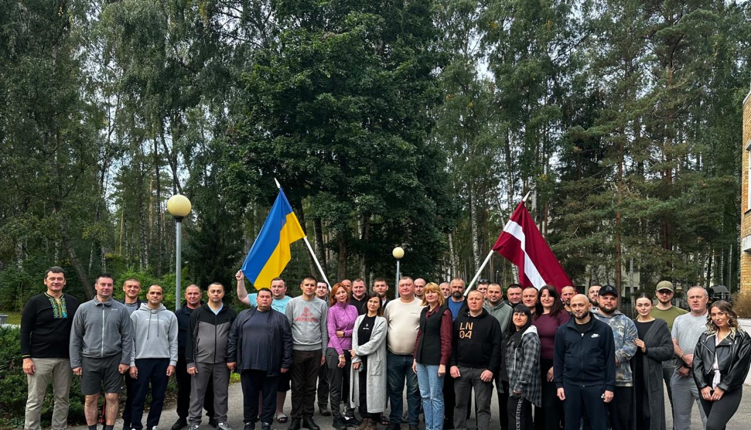 Ukrainas amatpersonu kopbilde nodaļas “Dzintari” teritorijā. Attēlā redzami 31 cilvēks; viens no viņiem tur Ukrainas karogu, bet otrs – Latvijas karogu.